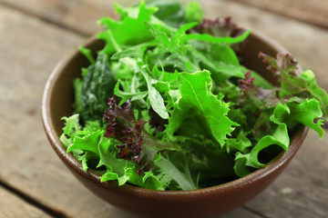 Bowl of mixed green salad on wooden table, closeup © Africa Studio