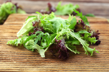 Mixed green salad on wooden cutting board, closeup