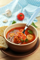 Tomato soup with meat balls on wooden spoon on wooden background