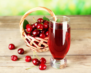 Glass of fresh juice with cherries on wooden table close up