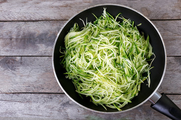 Grated zucchini and squash in pan on wooden table close up
