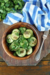 Sliced zucchini in bowl on wooden table, closeup