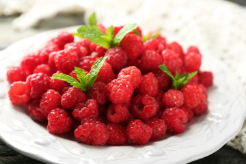 Sweet raspberries on plate on wooden  background