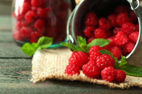 Sweet raspberries in decorative bucket on wooden  background