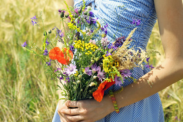 Woman holding beautiful bouquet of wildflowers outdoors
