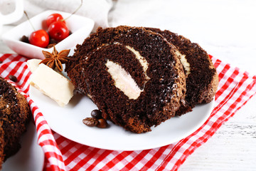 Delicious chocolate roll in white saucer on checkered napkin, closeup