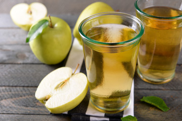Glasses of apple juice on wooden table, closeup