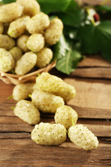 Fresh mulberry in wicker basket on wooden table, closeup