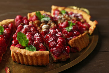 Tart with raspberries on tray, on wooden background