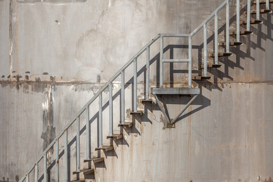 Closeup exterior stairs of refinery industrial storage tank.