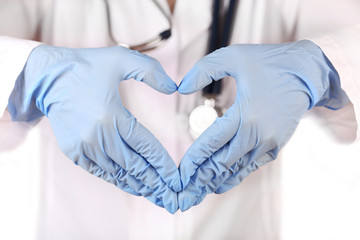 Fototapeta premium Doctor hands in gloves making shape of heart, closeup