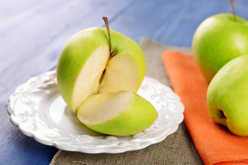 Sliced green apple in saucer on wooden table with napkins on wooden table, closeup