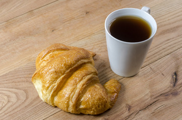 Breakfast cup of coffee and croissant.
