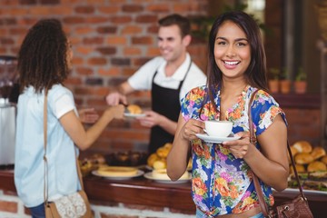 Smiling pretty customer holding cup of coffee