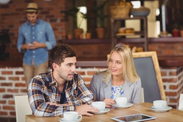 Two smiling friends talking and drinking coffee