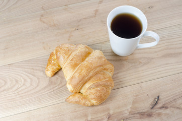 Breakfast cup of coffee and croissant.