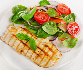 Salad with grilled chicken on white plate.