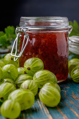Jar of gooseberry jam on a wooden table.