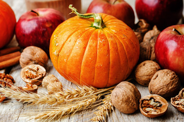 wood background with pumpkin, apples, wheat, honey and nuts