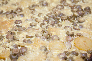 Closeup of baked potatoes with cheese and green olives
