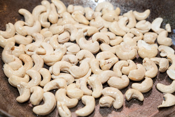 Closeup of raw cashew on frying pan with selective focus