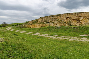 Fototapeta na wymiar General view toward crag of sedimentary rock in the field, Ludogorie, Bulgaria 