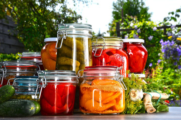 Fototapeta na wymiar Jars of pickled vegetables and fruits in the garden