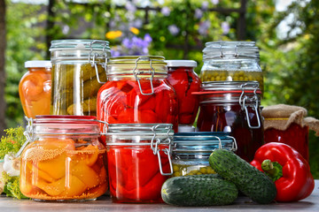 Fototapeta na wymiar Jars of pickled vegetables and fruits in the garden