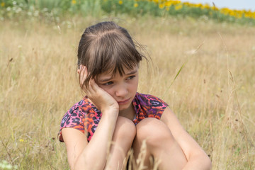 Sad and pensive girl in a field