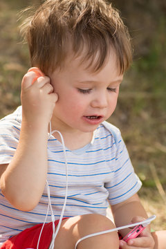Little cute kid listening to music on headphones