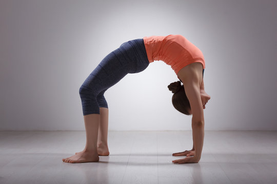 Beautiful sporty fit yogi girl practices yoga asana chakrasana