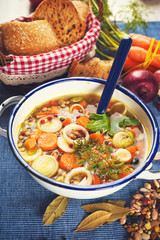 Vegetable soup in a metal bowl on a rural rustic wooden table.