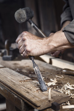hands of carpenter with a hammer and chisel