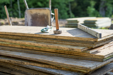 Mallet, protecting gloves and builders level on a pile of wooden