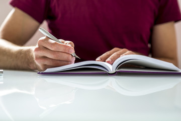 Close up of a student Writing Notes or Homework on a Clean Noteb