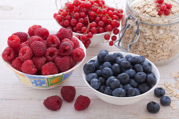 Breakfast - berries, fruit and muesli on white wooden