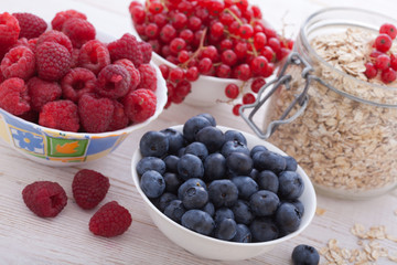 Breakfast - berries, fruit and muesli on white wooden
