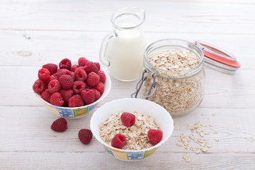 Breakfast - berries, fruit, milk and muesli on white wooden