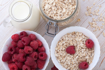 Breakfast - berries, fruit, milk and muesli on white wooden