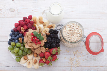Berries, fruit, milk and muesli Ingredients for healthy breakfast on wooden table