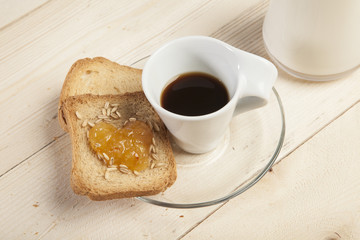 Fetta biscottata con marmellata a forma di cuore e tazzina di caffè