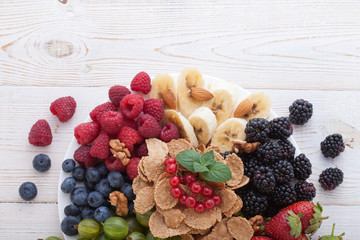 Breakfast - berries, fruit and muesli on white wooden