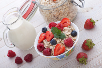 Breakfast - berries, fruit and muesli on white wooden