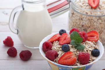 Breakfast - berries, fruit, milk and muesli on white wooden