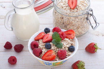 Breakfast - berries, fruit and muesli on white wooden