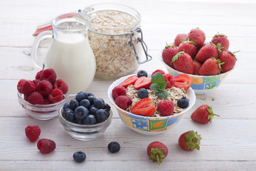Breakfast - berries, fruit and muesli on white wooden