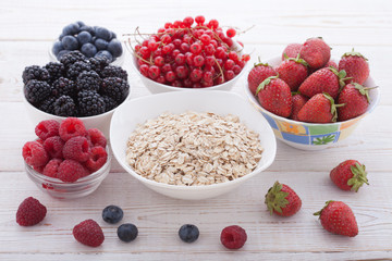 Breakfast - berries, fruit and muesli on white wooden