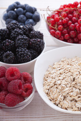 Breakfast - berries, fruit and muesli on white wooden