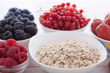 Breakfast - berries, fruit and muesli on white wooden