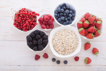 Breakfast - berries, fruit and muesli on white wooden